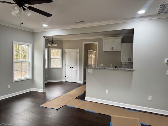 kitchen featuring light stone counters, crown molding, dark hardwood / wood-style flooring, white cabinets, and backsplash