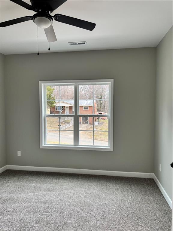 empty room with a healthy amount of sunlight, carpet flooring, and ceiling fan