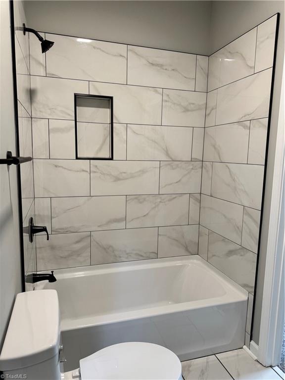 bathroom featuring toilet and tiled shower / bath combo