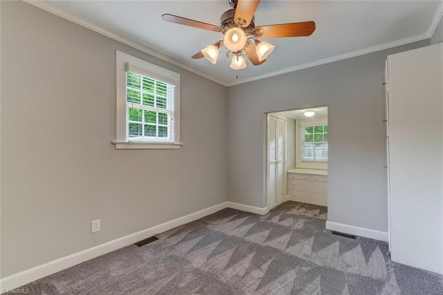 spare room featuring healthy amount of natural light, baseboards, carpet floors, a ceiling fan, and crown molding