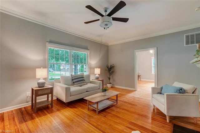 living room featuring light wood-style floors, healthy amount of natural light, a ceiling fan, crown molding, and baseboards