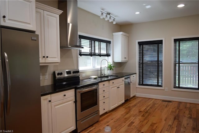 5170 Tabernacle School Rd, Asheboro, NC 27205 - kitchen with stainless steel appliances, wall chimney exhaust hood, white cabinetry, light wood finished floors, and plenty of natural light