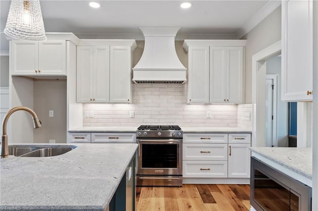 kitchen featuring a sink, stainless steel appliances, white cabinets, and custom range hood