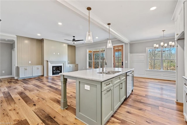 kitchen with light wood finished floors, crown molding, dishwasher, a fireplace, and a sink