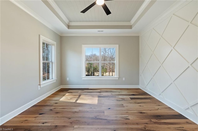 empty room featuring baseboards, a tray ceiling, ceiling fan, hardwood / wood-style flooring, and crown molding