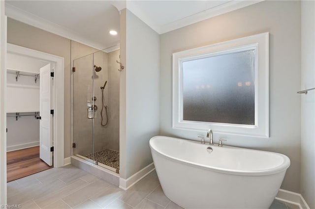 bathroom featuring a freestanding tub, baseboards, a spacious closet, and a shower stall