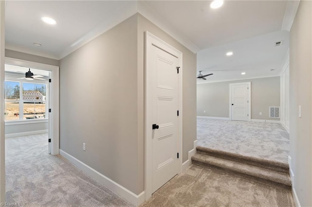 hall with visible vents, light carpet, baseboards, and crown molding