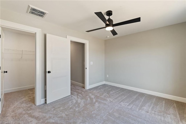 unfurnished bedroom featuring visible vents, a walk in closet, baseboards, and carpet floors