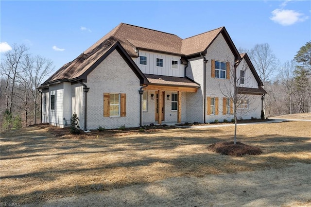 modern farmhouse with brick siding, board and batten siding, and a front yard