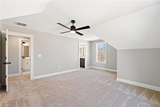 additional living space featuring visible vents, baseboards, lofted ceiling, light carpet, and a ceiling fan