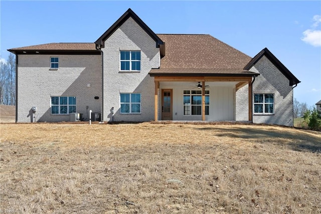 back of property with brick siding, central AC, a ceiling fan, and a lawn