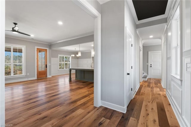 corridor with baseboards, an inviting chandelier, wood finished floors, and crown molding