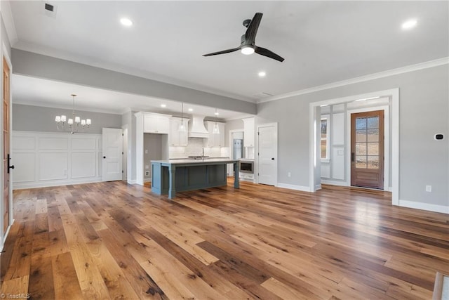 kitchen with open floor plan, ornamental molding, decorative backsplash, light wood-style flooring, and white cabinetry