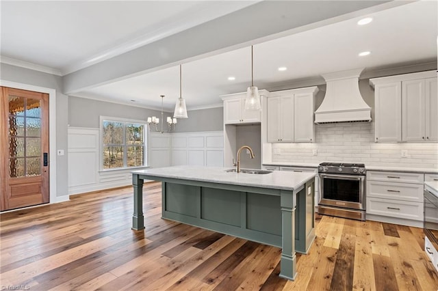 kitchen with gas stove, custom exhaust hood, ornamental molding, a sink, and white cabinetry