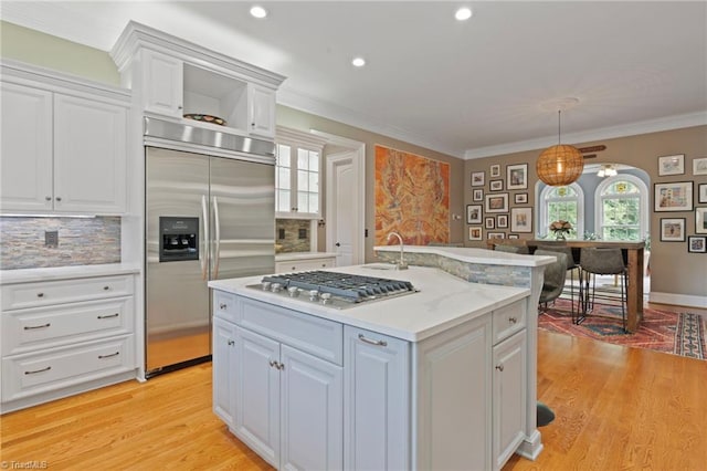 kitchen featuring decorative light fixtures, light hardwood / wood-style flooring, backsplash, and stainless steel appliances