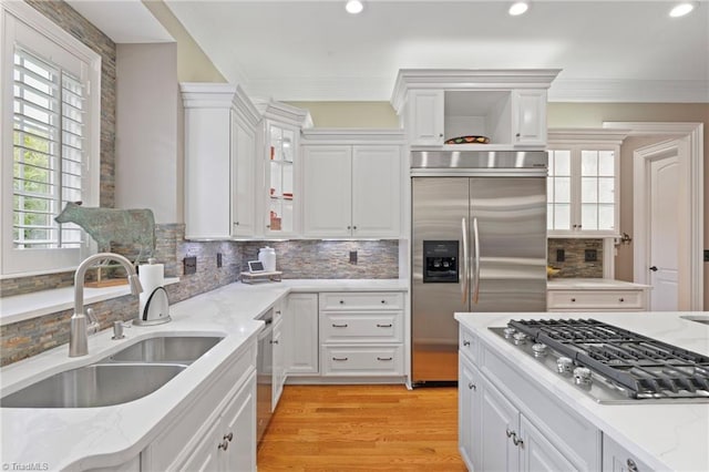 kitchen with light hardwood / wood-style flooring, stainless steel appliances, white cabinets, sink, and decorative backsplash