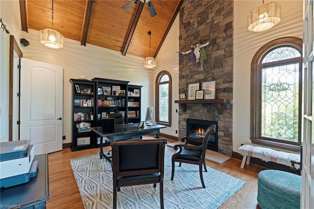 office area with wood ceiling, beamed ceiling, hardwood / wood-style floors, a stone fireplace, and high vaulted ceiling