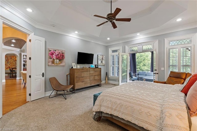 bedroom featuring hardwood / wood-style floors, ceiling fan, a tray ceiling, and ornamental molding