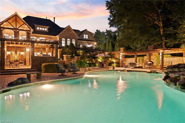 pool at dusk featuring a pergola and a patio