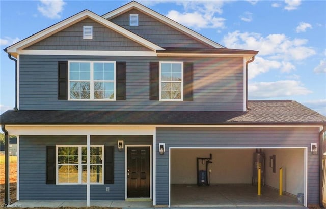 craftsman-style house featuring roof with shingles, covered porch, and driveway