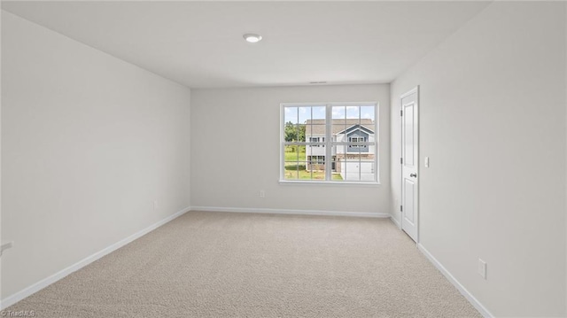 spare room featuring baseboards and light carpet