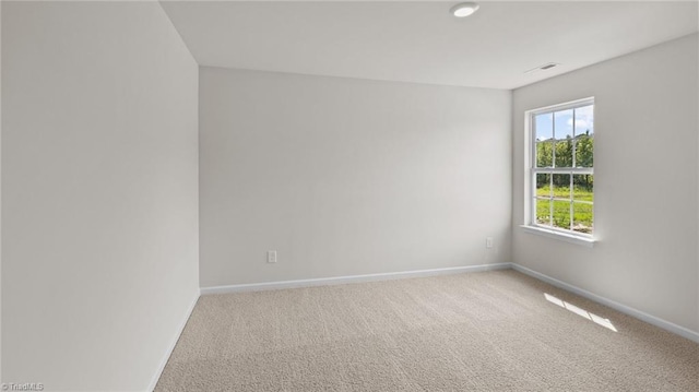 empty room featuring light carpet, visible vents, and baseboards