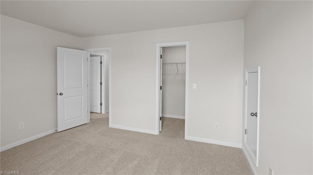 unfurnished bedroom with a closet, baseboards, a walk in closet, and carpet