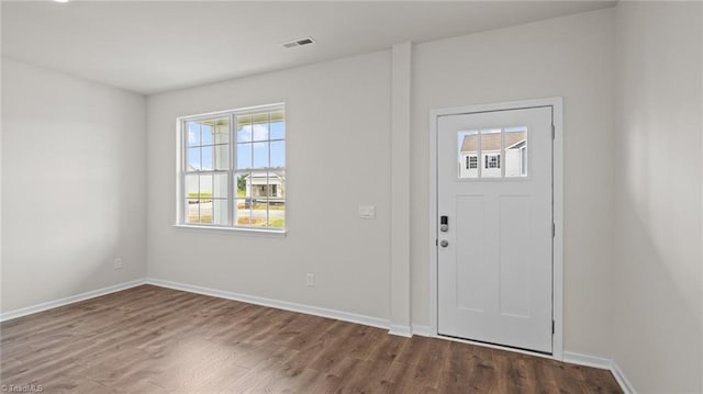 foyer with dark wood finished floors, visible vents, and baseboards