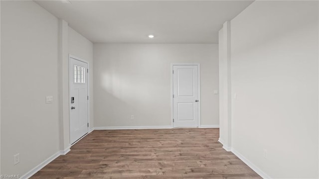 unfurnished room with recessed lighting, wood finished floors, and baseboards