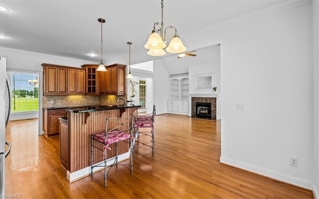 7103 Ludgate Rd, Gibsonville, NC 27249 - kitchen with a chandelier, dark countertops, brown cabinetry, a breakfast bar, and wood finished floors