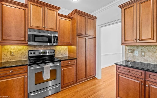 7103 Ludgate Rd, Gibsonville, NC 27249 - kitchen with appliances with stainless steel finishes, light wood-style floors, brown cabinets, dark stone counters, and ornamental molding