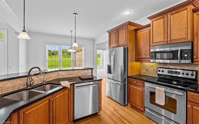 7103 Ludgate Rd, Gibsonville, NC 27249 - kitchen featuring appliances with stainless steel finishes, ornamental molding, light wood-style flooring, brown cabinetry, and pendant lighting