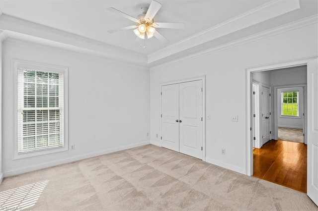 7103 Ludgate Rd, Gibsonville, NC 27249 - unfurnished bedroom with crown molding, a tray ceiling, light carpet, a closet, and a ceiling fan