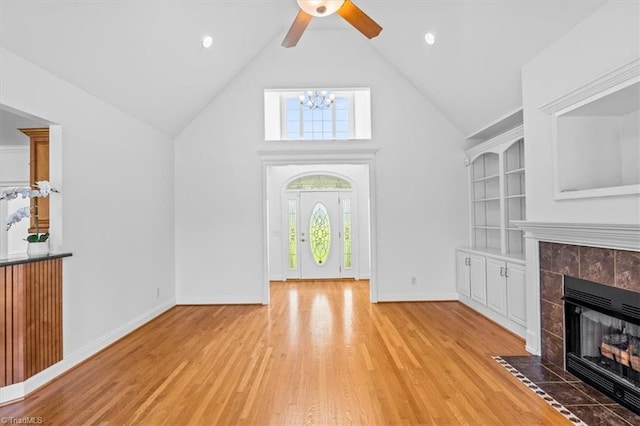 7103 Ludgate Rd, Gibsonville, NC 27249 - unfurnished living room with light wood finished floors, high vaulted ceiling, a tiled fireplace, a ceiling fan, and a chandelier