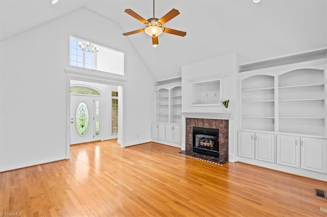 7103 Ludgate Rd, Gibsonville, NC 27249 - unfurnished living room featuring ceiling fan, high vaulted ceiling, light wood-type flooring, a tiled fireplace, and built in shelves