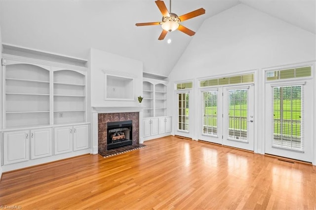 7103 Ludgate Rd, Gibsonville, NC 27249 - unfurnished living room with high vaulted ceiling, ceiling fan, a tiled fireplace, built in features, and wood finished floors