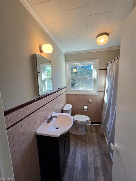 bathroom with hardwood / wood-style floors, toilet, tile walls, vanity, and ornamental molding