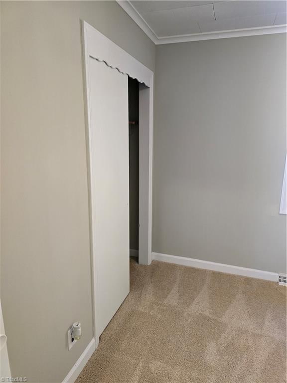 unfurnished bedroom with ornamental molding, carpet floors, and a closet