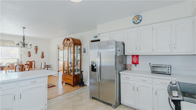 kitchen with stainless steel refrigerator with ice dispenser, white cabinetry, pendant lighting, and a notable chandelier