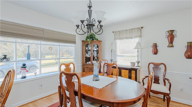 dining space with light wood-type flooring, a wealth of natural light, and an inviting chandelier