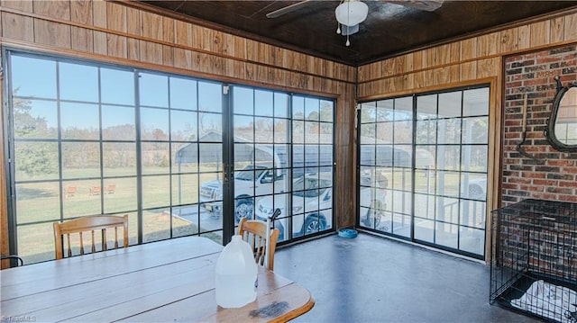 dining room featuring ceiling fan, a wealth of natural light, and wood walls