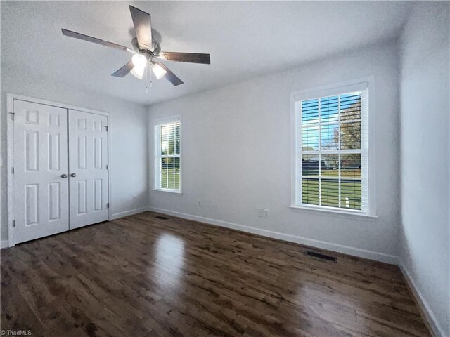 unfurnished bedroom with dark wood-type flooring, ceiling fan, and a closet