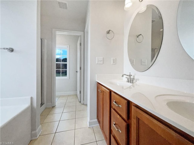 bathroom with a bath, vanity, and tile patterned flooring