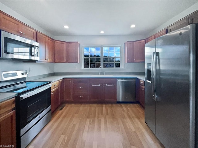 kitchen with light wood-type flooring, appliances with stainless steel finishes, and sink