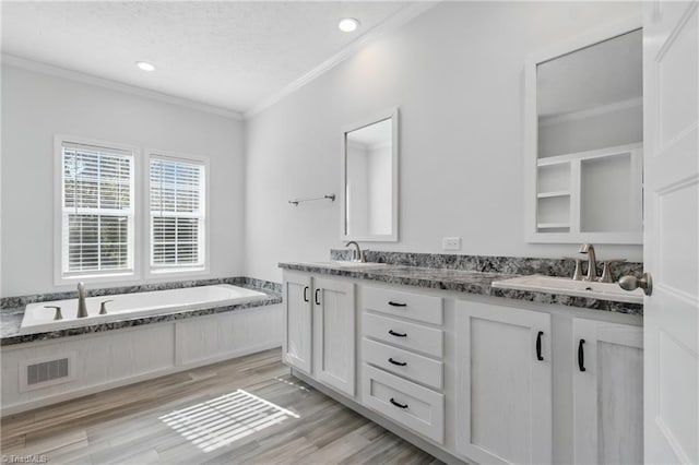 2875 Motsinger Rd, Winston-Salem, NC 27107 - bathroom featuring double vanity, ornamental molding, a garden tub, wood finished floors, and a textured ceiling