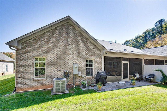 rear view of house with a lawn, central AC, and a patio area