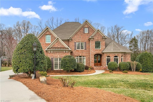 view of front of home with brick siding, roof with shingles, and a front lawn