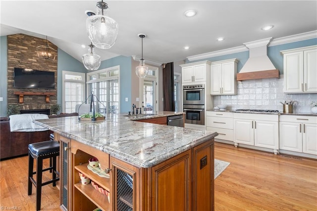 kitchen featuring a spacious island, custom exhaust hood, a fireplace, appliances with stainless steel finishes, and open floor plan