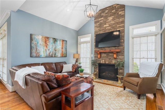 living area with high vaulted ceiling, light wood-type flooring, a notable chandelier, and a fireplace