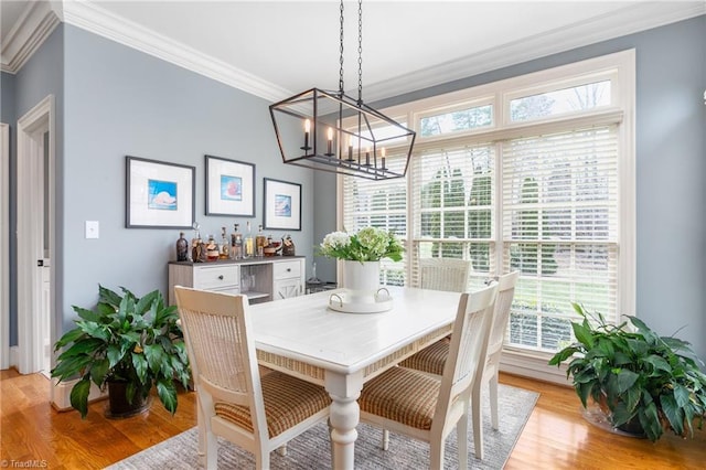 dining space with an inviting chandelier, light wood finished floors, and ornamental molding